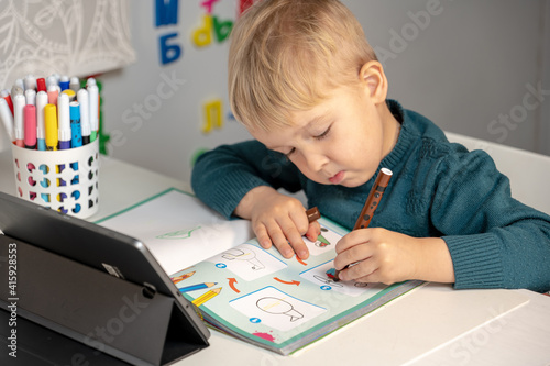 online training. the boy sits at the computer in the room and does his homework