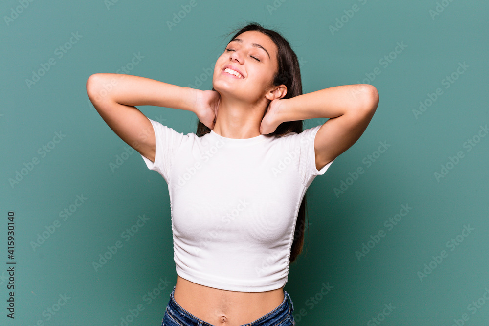 Young Indian woman isolated on blue background feeling confident, with hands behind the head. Young Indian woman isolated on blue background feeling confident, with hands behind the head.