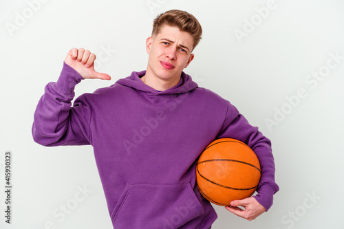 Young caucasian man playing basketball isolated background feels proud and self confident, example to follow.