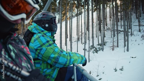 Couple of skiers sitting in chair lift going up a snowy mountain. Ski elevator lifts people transportation. Luxury ski resort. Winter activities.