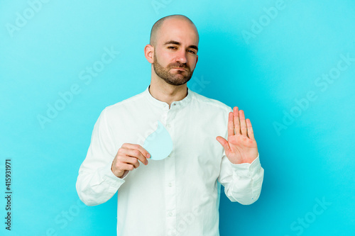 Young caucasian bald man celebrating world water day isolated on blue background standing with outstretched hand showing stop sign, preventing you.