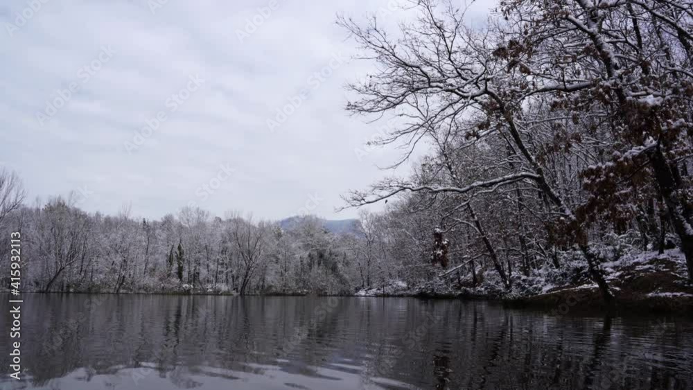 Beautiful lake with calm cold water reflecting forest trees covered in white snow Beautiful lake with calm cold water reflecting forest trees covered in white snow