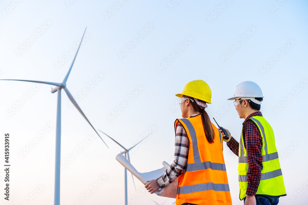 engineer team analyze a blueprint drawing of wind turbine farm engineer team analyze a blueprint drawing of wind turbine farm