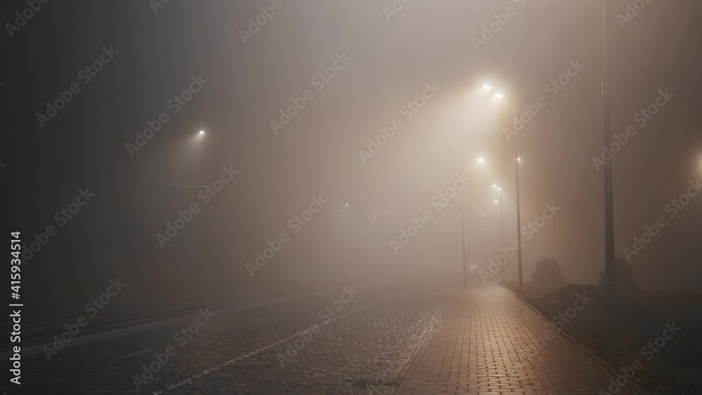 Mystical autumn street with thick atmospheric smoke. Foggy evening. Night time. Mysterious thriller scene with no people.
