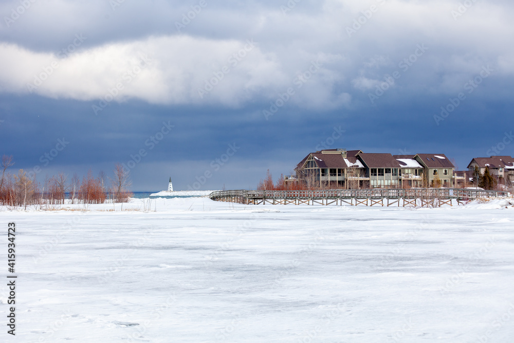 An old, wooden bridge crosses a section of frozen Bay