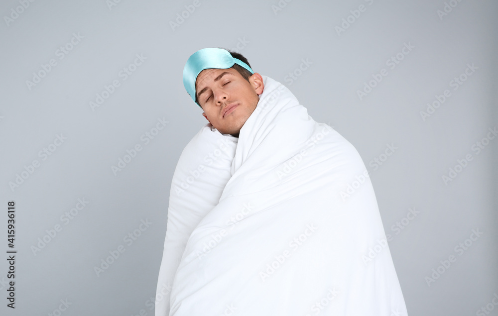 Man wrapped in blanket sleeping on grey background. Space for text Man wrapped in blanket sleeping on grey background. Space for text