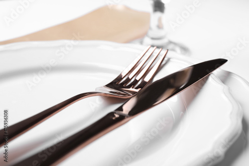Plates with golden cutlery on table  closeup