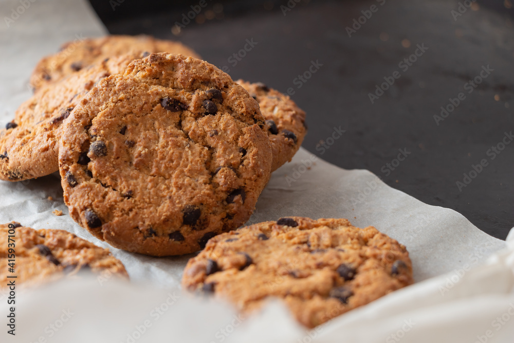 Crispy oatmeal cookies with chocolate on baking paper. Homemade cakes. Crispy oatmeal cookies with chocolate on baking paper. Homemade cakes.