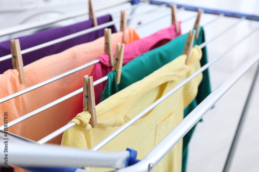 Clean laundry hanging on drying rack indoors, closeup