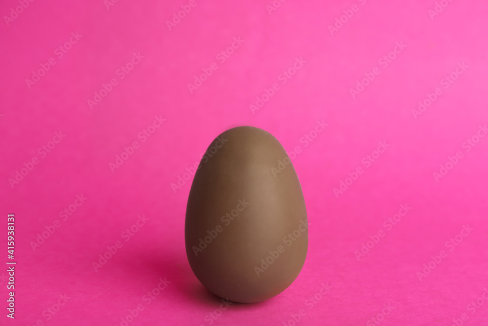 One sweet chocolate egg on pink background One sweet chocolate egg on pink background
