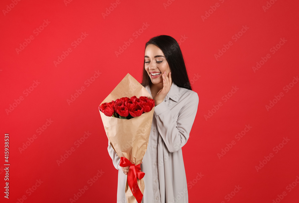 Happy woman with tulip bouquet on red background. 8th of March celebration Happy woman with tulip bouquet on red background. 8th of March celebration