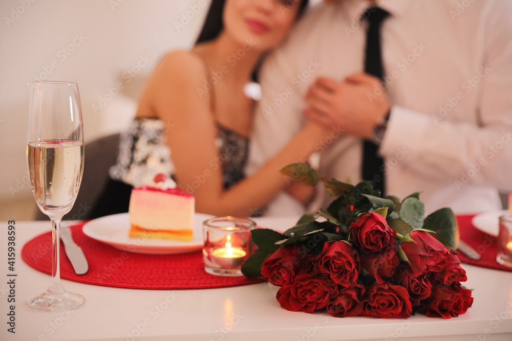 Happy couple celebrating Valentine's day indoors, focus on bouquet and champagne Happy couple celebrating Valentine's day indoors, focus on bouquet and champagne