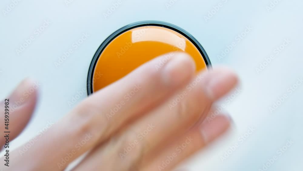 Young woman pushing orange button with a finger and palm of her hand. Press a round glossy button close up. Activation, launching something. Turn on and off.