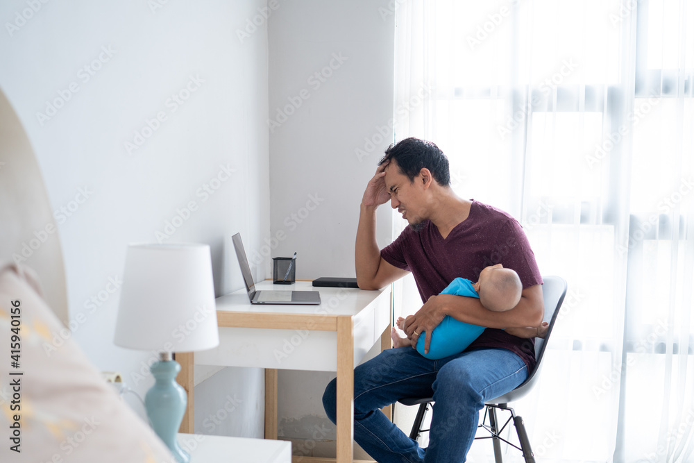 portrait of a stress busy father working from home while holding his infant baby portrait of a stress busy father working from home while holding his infant baby