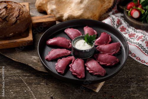 Delicious traditional Russian dumplings, handmade dough painted with beets. Still life on a wooden board. Close-up. photo