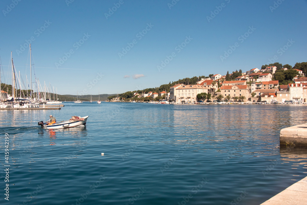 Croatia, Brac, Milna. Fisherman returns to quay calm morning.