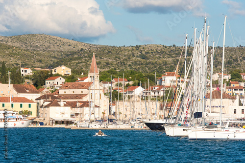 Croatia, Brac, Milna. Fisherman dwarfed by sailboats in crowded Milna marina.
