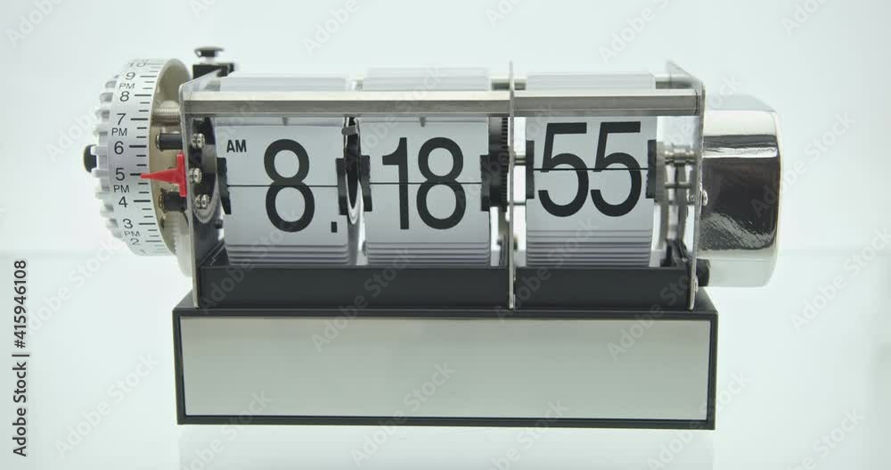Flip clock or flap clock on white table. An electromechanical, digital time keeping device with time indicated by numbers sequentially revealed by a split-flap display, operates only in one direction.