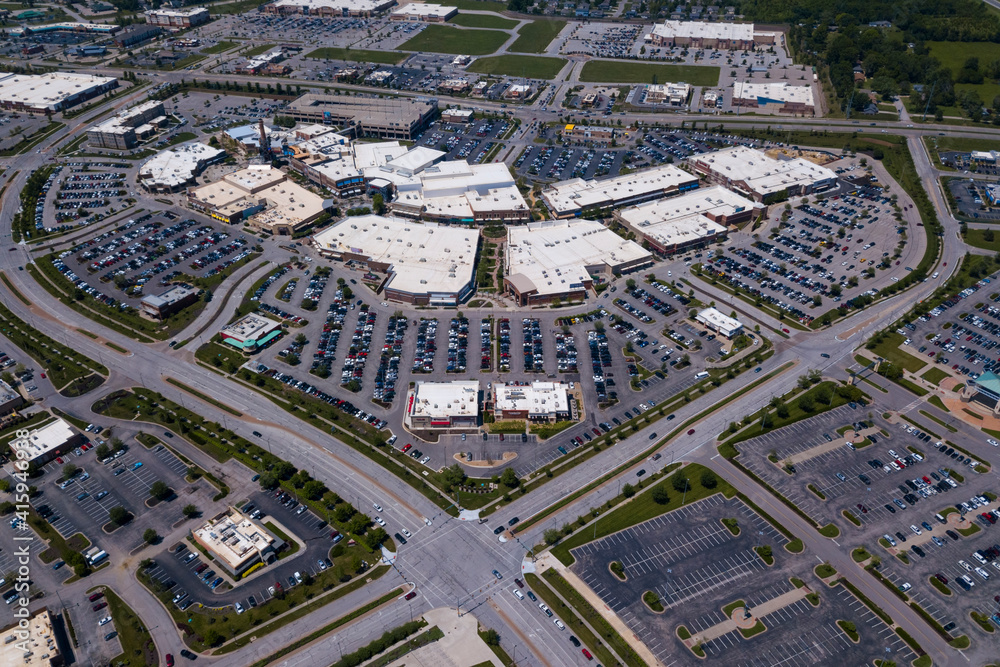 Aerial drone photo of a busy shopping retail center with cars in the parking lot.
