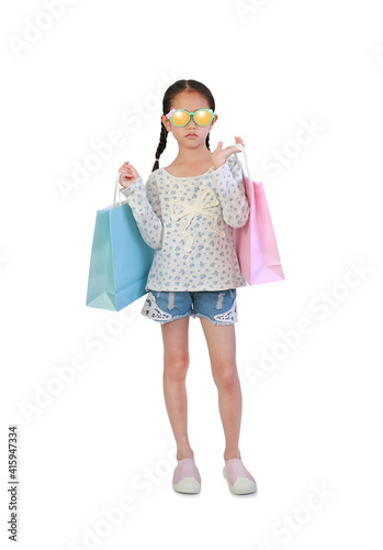 Portrait Asian little child wearing sunglasses holding shopping bags isolated on white background with clipping path. Front view and Full length