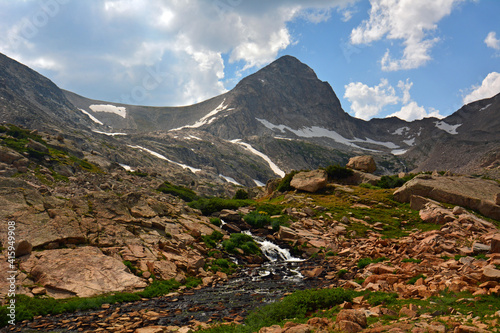 magnificent arapahoe, navajo, and shoshoni peaks with a mountain stream and snowfield on a sunny summer day along the lake isabele trail in the indian peaks wilderness area near nederland, colorado photo