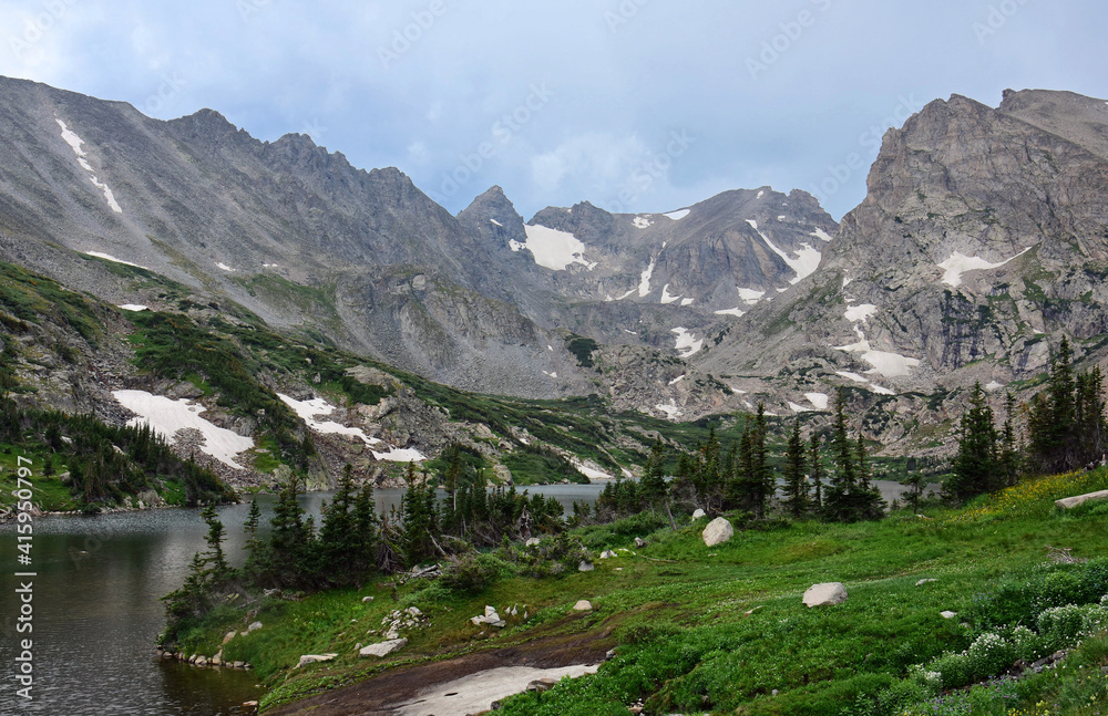 magnificent arapahoe, navajo, and shoshoni peaks with a mountain stream and snowfield on a sunny summer day along the lake isabele trail in the indian peaks wilderness area near nederland, colorado