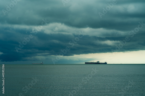 Seaview with ships in Port Dickson. Heavy clouds in rainy season. The image contain soft focus, noise and grain.
