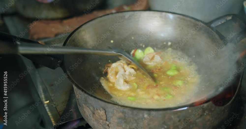 Chef cooking Stir Frying bitter beans with shrimps in pan , traditional spicy food Southern Thailand, handheld shot. Chef cooking Stir Frying bitter beans with shrimps in pan , traditional spicy food Southern Thailand, handheld shot.