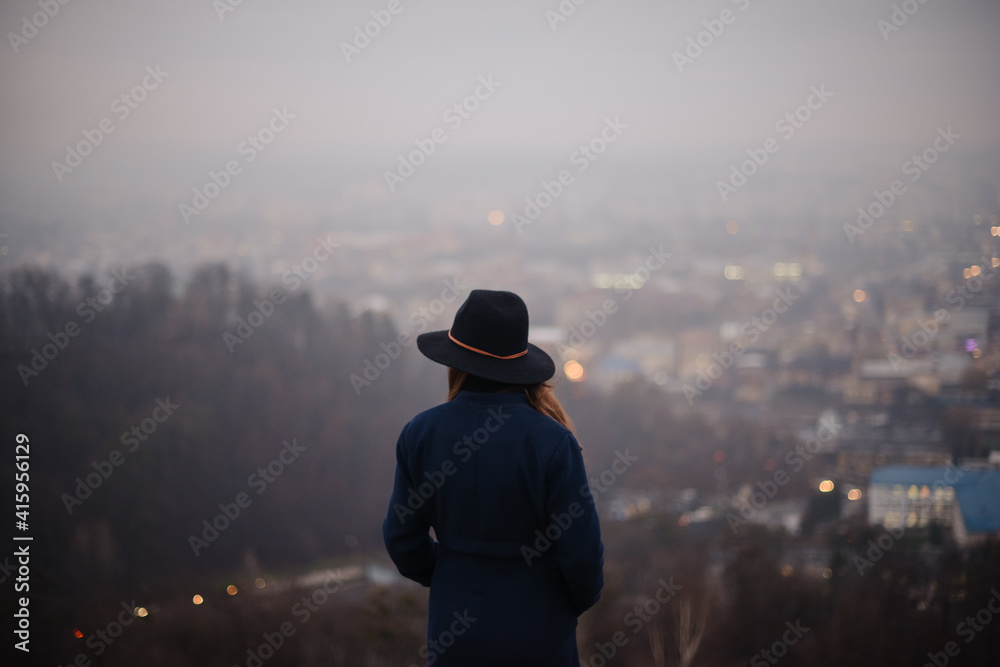 Back view of woman in hat standing on hill of autumn park Back view of woman in hat standing on hill of autumn park