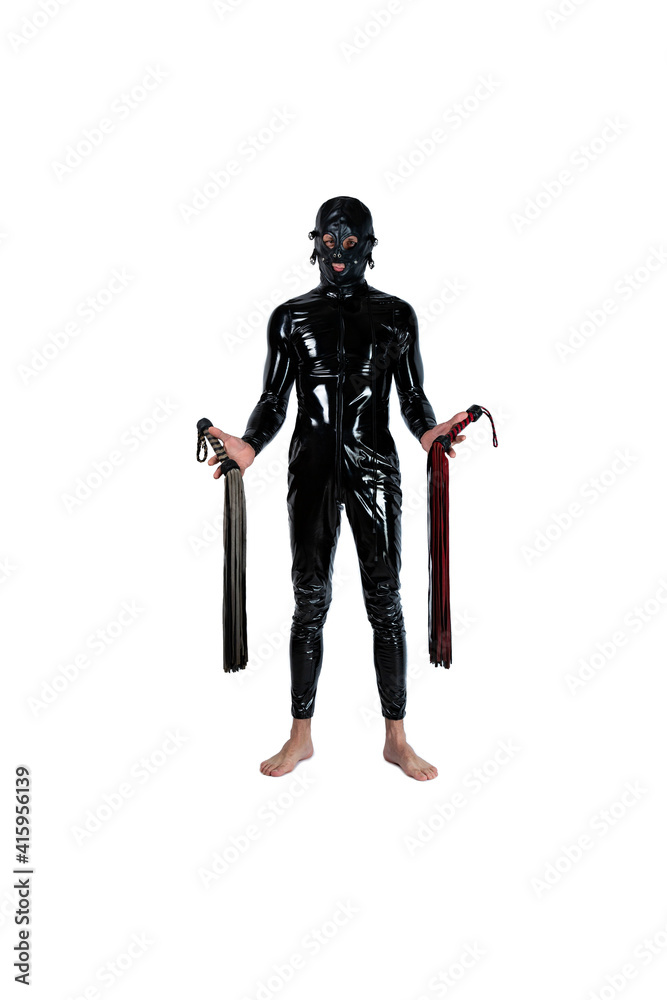slave stands in latex fetish clothes catsuit and pvc mask with a whips in her hands. bdsm costume for role-playing adult games. Dominant holding a leather whip Flogger for BDSM sex with spanking slave stands in latex fetish clothes catsuit and pvc mask with a whips in her hands. bdsm costume for role-playing adult games. Dominant holding a leather whip Flogger for BDSM sex with spanking
