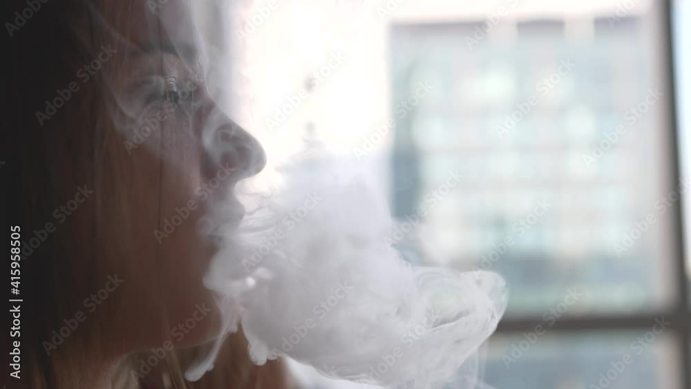the girl smokes the vape blows smoke from her mouth in slow motion the girl smokes the vape blows smoke from her mouth in slow motion