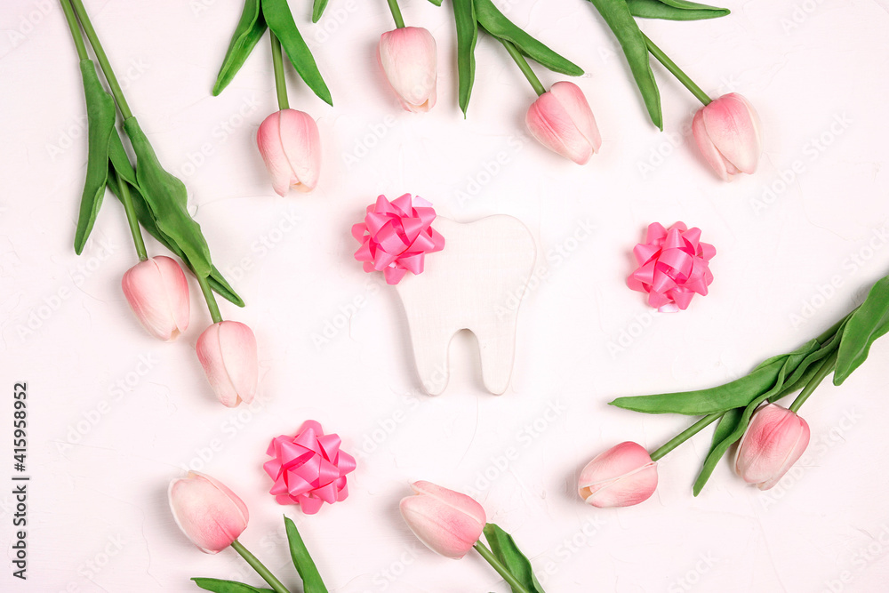 Festive dental background with tooth, bows and pink tulips on a white background with copy space for text.