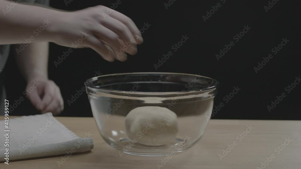 A person puts dough in a bowl and then covers A person puts dough in a bowl and then covers