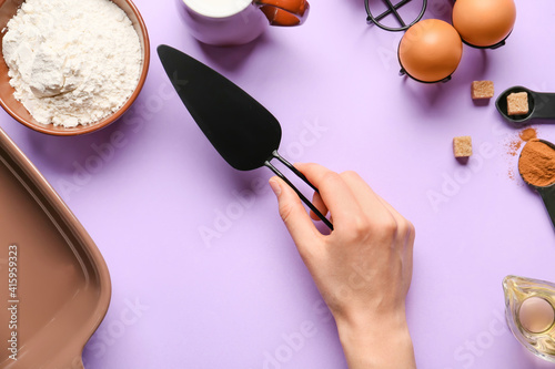 Female hand with cake spatula on color background