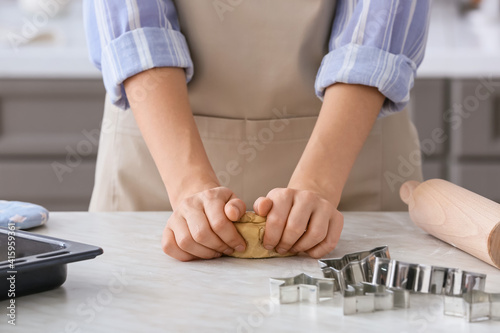 Woman making dough on table in kitchen