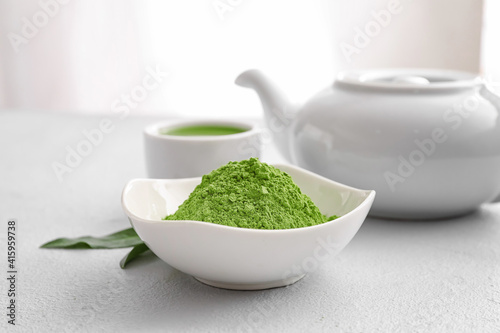 Bowl with powdered matcha tea, teapot and cup on table