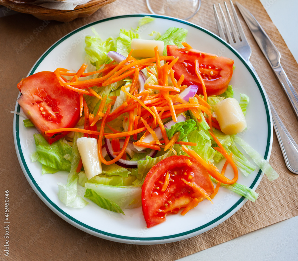Delicious vegetable salad with iceberg, tomato, carrot, marinated white asparague and onion