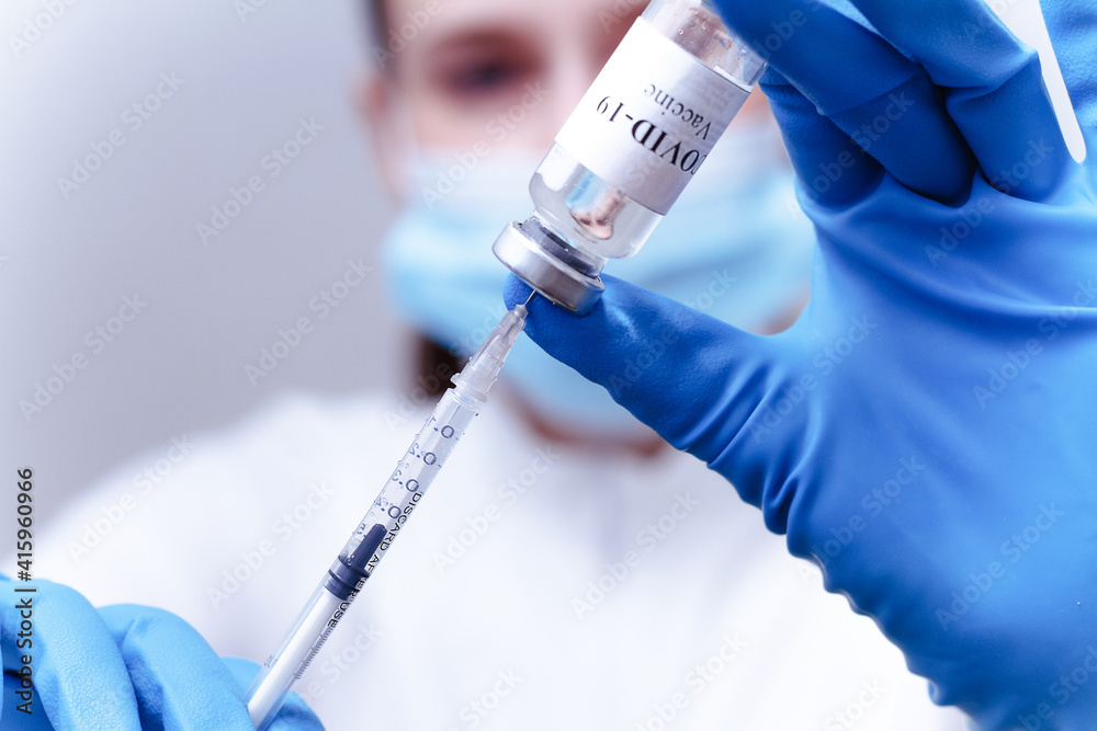 Doctor in a mask fills the syringe with medicine from the bottle while preparing Doctor in a mask fills the syringe with medicine from the bottle while preparing