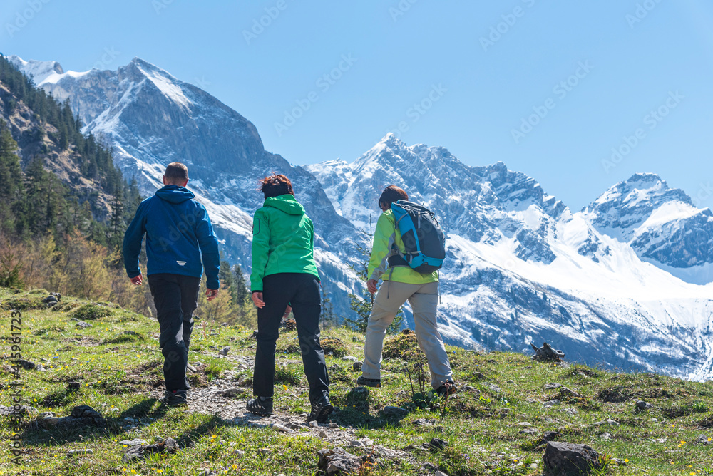 Drei Wanderer genießen die frühlingshafte Natur bei einer Bergtour in den Allgäuer Alpen