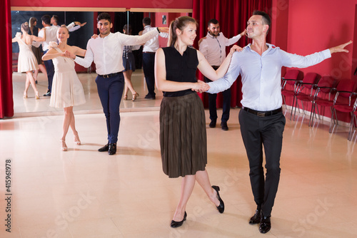 Young positive people dancing samba in pairs in dance hall