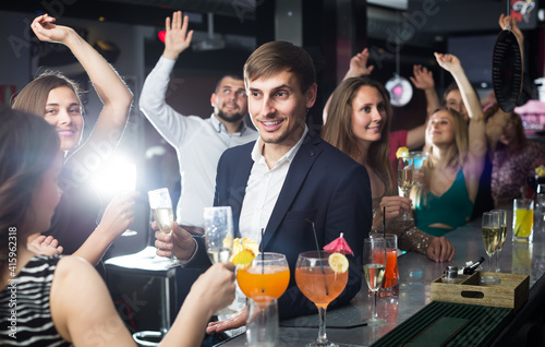 Men and women are dancing in a restaurant with cocktails in their hands
