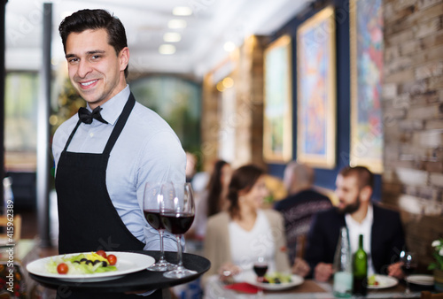 Portrait of smiling waiter with a serving tray in restaurant