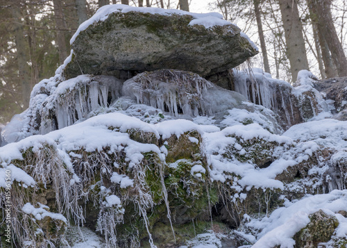 frozen fast flowing spring water, icy rocks and water stream, frosty tree roots, beautiful ice and water texture