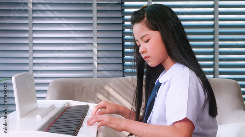 A young girl intends to practice playing the piano at home. photo