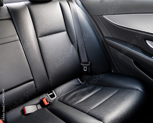 Back passenger black leather seats in modern luxury car. Black perforated leather with stitching. Car inside. Leather comfortable red seats. Car interior details © Aleksei