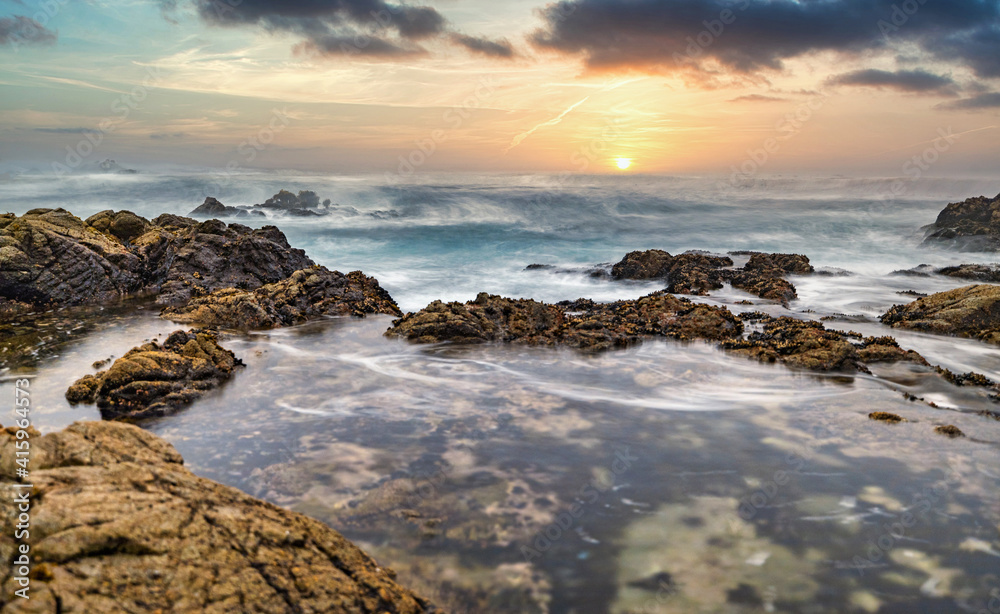 Beautiful seascape, ocean views, rocky coastline, sunlight on the horizon. Composition of nature. Sunset scenery background. Cloudy sky. Reflection of water. California coast. Shot with a long Beautiful seascape, ocean views, rocky coastline, sunlight on the horizon. Composition of nature. Sunset scenery background. Cloudy sky. Reflection of water. California coast. Shot with a long