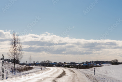 Winter road under blue sky white clouds.Rural road asphalt.
