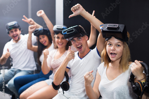 Cheerful friends are wearing virtual reality goggles and giving thumbs up.