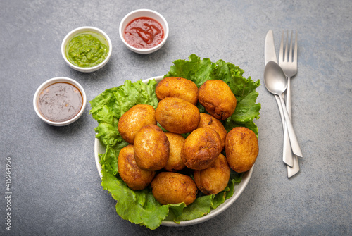 bread rolls stuffed with potatoes placed on a lettuce leaf served with green and red sauces