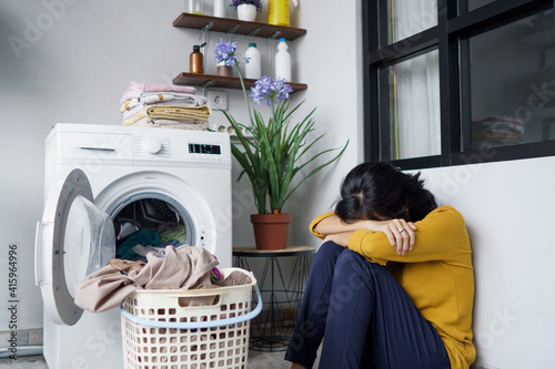 stressed pretty asian housewife doing some laundry at home photo